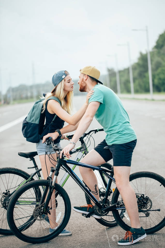 浪漫运动情侣接吻对模糊背景与自行车
