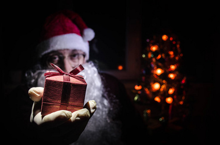 圣诞老人拿着节日礼物的背景。圣诞老人手里拿着礼物。选择性焦点。深色色调背景
