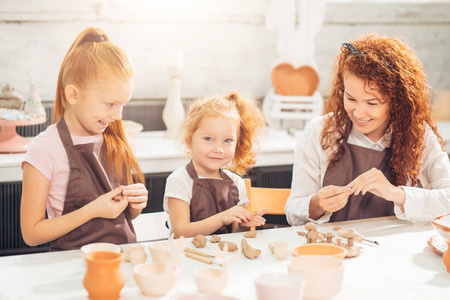 红头发的母亲和孩子的女儿在家里塑造粘土和一起玩