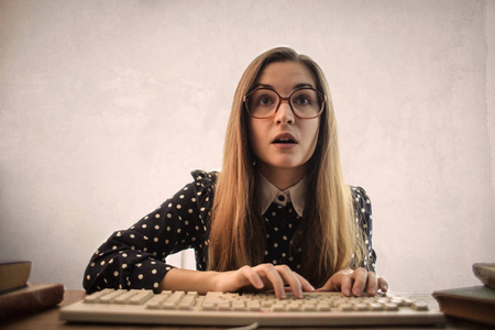 戴眼镜的年轻女子在键盘上发短信