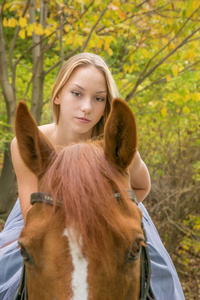 一个年轻的金发女郎摆着一匹马, 一个漂亮的女孩和一匹强壮的马