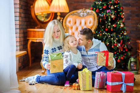 圣诞节的早晨，一个幸福的大家庭互相赠送礼物，坐在圣诞树附近