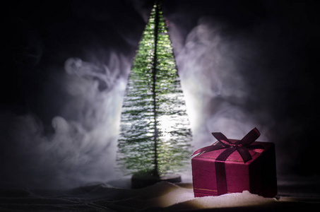 雪上的红色圣诞礼盒和杉树。 圣诞家居装饰与雪和树在黑暗的背景与复制空间。 选择性聚焦。 新一年的背景属性