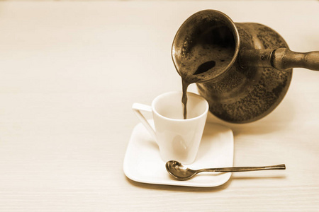 咖啡倒在白瓷杯里，用一个古老的铜咖啡壶煮咖啡