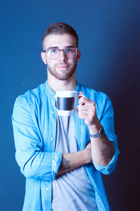 英俊的年轻男子站在捧着一杯咖啡在他手中的画像