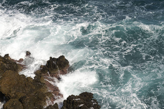 海浪在多石的海滩上形成一朵浪花波和溅上海滩岩石上的海浪