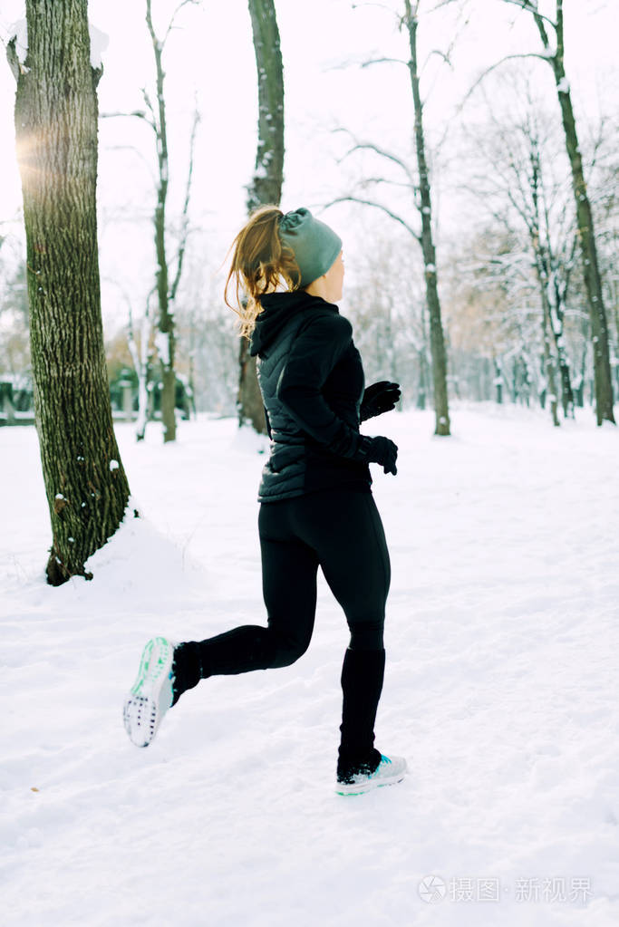 女运动员冬天在公园里慢跑公园周围下雪