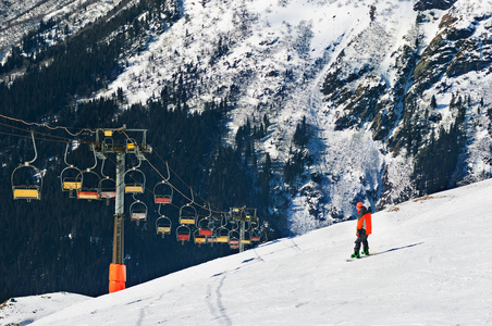 滑雪升降机下斜坡下的滑雪者。缆车在山