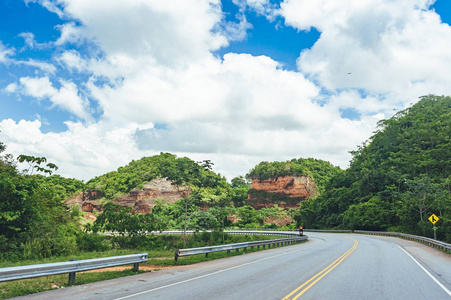 穿越森林和丘陵的道路，背景是多云的天空