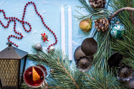 在蓝色背景上有橙色八角豆蔻和肉桂的热的温热的葡萄酒。圣诞树树枝, 礼物和锥体