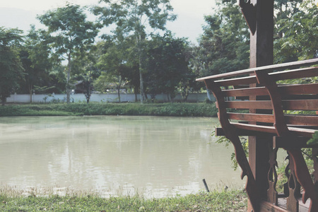 木长凳在凉亭在池塘的水边公园