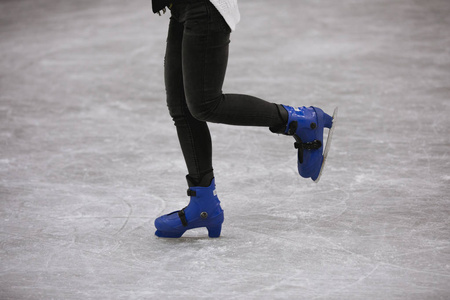 在溜冰场滑冰的妇女的腿的被剪的射击