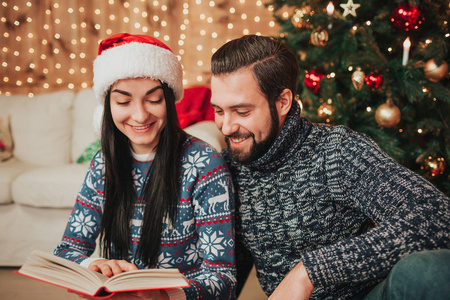 圣诞快乐, 新年快乐。年轻夫妇在家里庆祝节日。一男一女正在看书