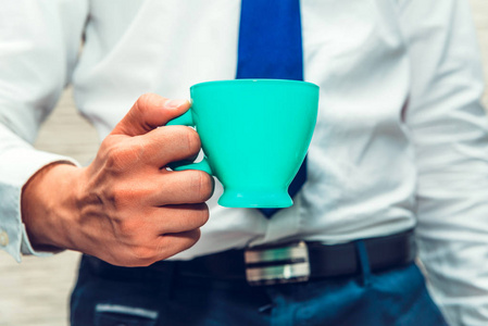 这个人手里拿着一个绿色绿松石咖啡杯，一个商人正在做一个商业概念的活动。