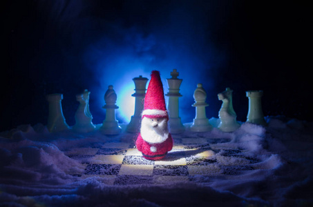 在雪地里下棋。冬天的概念。圣诞节或新年礼物在一个棋盘上的圣诞老人在黑暗的背景。复制空间