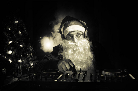 Dj 圣诞老人混合了一些圣诞欢呼。暗迪斯科俱乐部色调的背景。新年前夜的活动在光线的照射下。有用的海报。选择性焦点