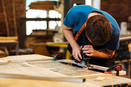 工厂工人塑造木板的肖像，以制作木工车间家具的一部分