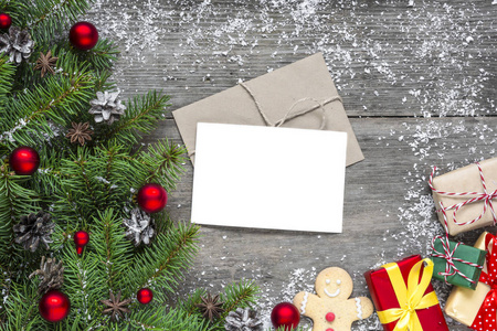 圣诞贺卡与冷杉树枝, 装饰品和礼物箱子在质朴的木背景