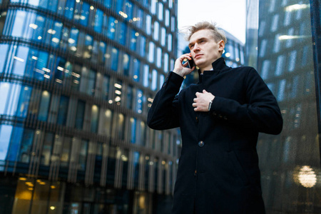 青年企业家在户外进行电话交谈时感觉寒冷，视角低