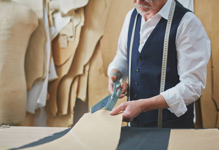 在阿泰利埃商店做衣服时,熟练裁缝裁剪织物图案的肖像.照片