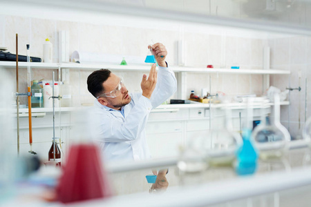 现代科学家在实验室工作的肖像，用有色液体检查试管中的化学反应