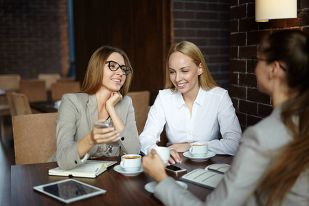 吸引人的年轻经理聚集在可爱的咖啡馆,讨论他们的联合项目小组肖像的