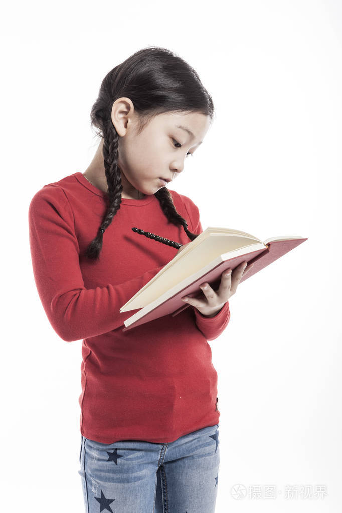 小女孩拿着一本书,站在画室里,隔着白色的背景