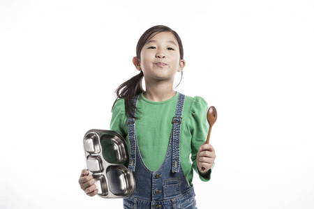 可爱的亚洲女孩拿着盘子和木勺。