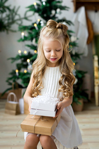 带着圣诞礼物盒的快乐微笑的小女孩。 圣诞快乐，节日快乐