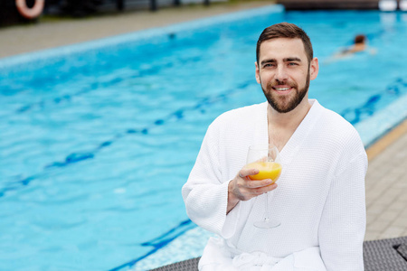 无胡子的人，带着一杯饮料，在度假胜地的游泳池里放松