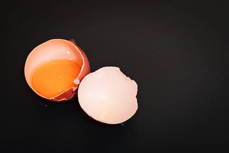 食物概念鸡蛋黄,鸡蛋壳在黑色石板上,带有复制空间照片