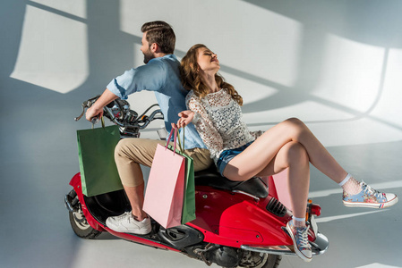时尚情侣爱上了坐在红色滑板车上的购物袋