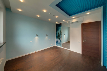 房间有一面蓝色的墙和内置的滑动衣柜，有一扇木棕色的门