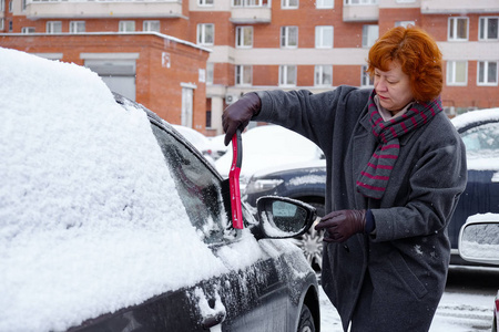 一个女人从车里清理积雪