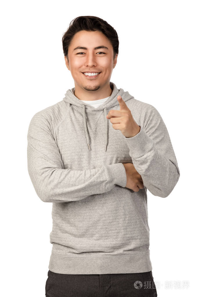 一个20多岁的有魅力的男人站在白色的背景下,穿着灰色的罩衫,微笑着
