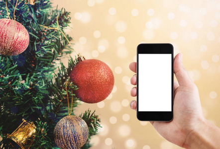 手持手机，空白白色屏幕，圣诞树装饰，金色背景