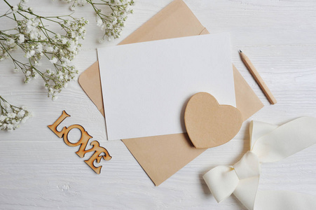 用一颗心形的爱盒来模拟字母, 在一张木质的白色桌子上, 上面有满天星花, 情人节的贺卡上放着你的文字。平躺, 顶部查看照片