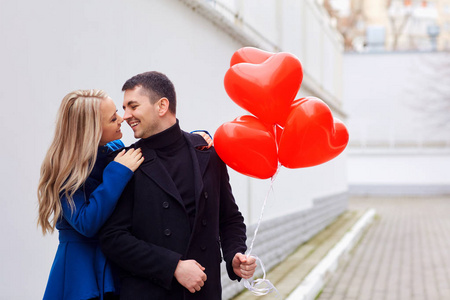 爱的情侣与红色的心气球在街上