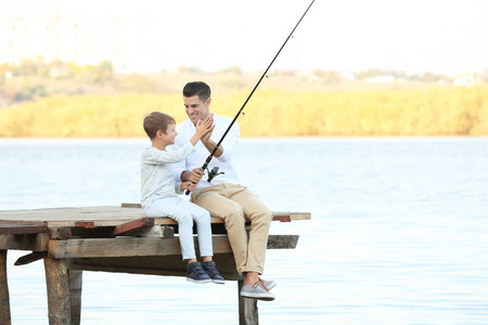 父亲和他的儿子从码头上河钓鱼