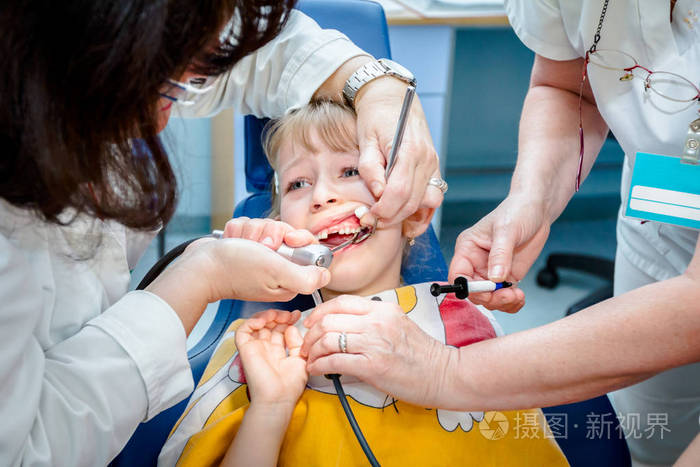 被吓坏的可爱的小女孩张开嘴在牙医牙科