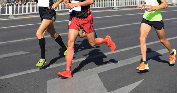 马拉松赛跑运动员的腿在城市道路上奔跑
