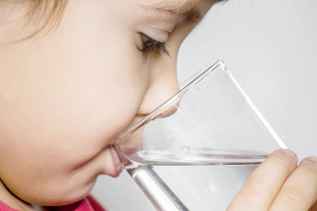 一个孩子拿着一杯水。 选择性聚焦。