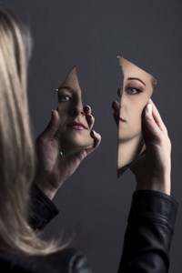 女人看着她的脸在两个破碎的镜子碎片