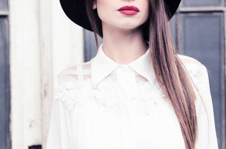 商业女人。 女性服装的细节。 穿白色蕾丝衬衫黑色帽子和红色嘴唇的女孩。