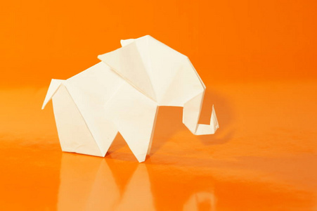 白色折纸斯隆. 一只纸白大象被隔离在明亮的彩色背景上. 日本艺术.