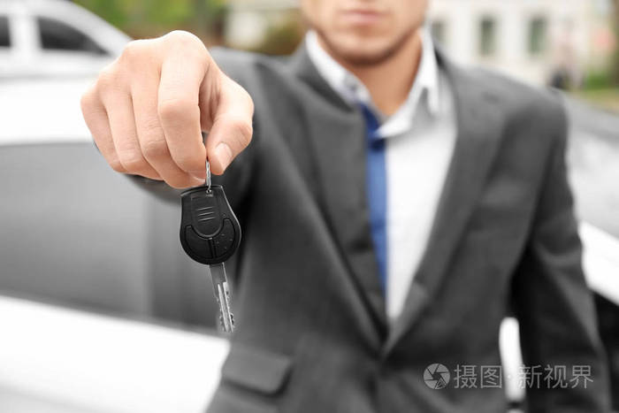 办公室男穿着拿着车钥匙在户外