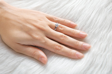 s hand with luxury engagement ring on fur, closeup