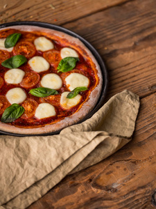 带有罗勒西红柿饼和马扎里拉片的披萨在木桌上，上面有餐巾纸和复印空间