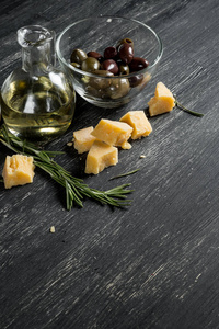 黑木桌上有橄榄奶酪和橄榄油的碗