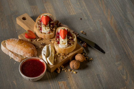 碗的顶部视图，在木板和刀上有水果果酱三明治。